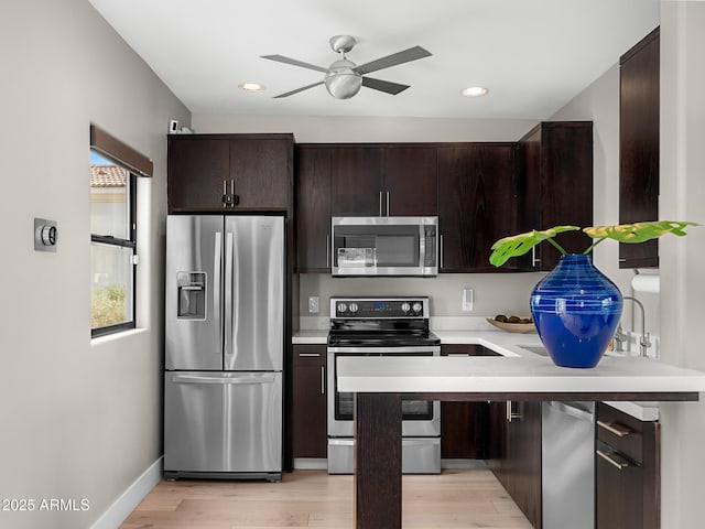 kitchen with light countertops, appliances with stainless steel finishes, light wood-style flooring, and dark brown cabinets