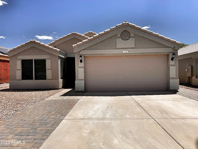 view of front of property with concrete driveway, stucco siding, a garage, and a tile roof