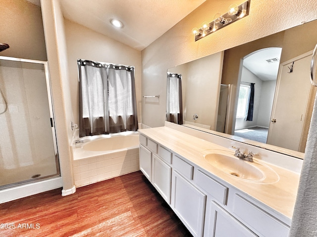 bathroom featuring vaulted ceiling, wood finished floors, a shower stall, a bath, and vanity
