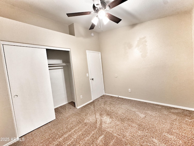 unfurnished bedroom with carpet, a closet, baseboards, ceiling fan, and vaulted ceiling