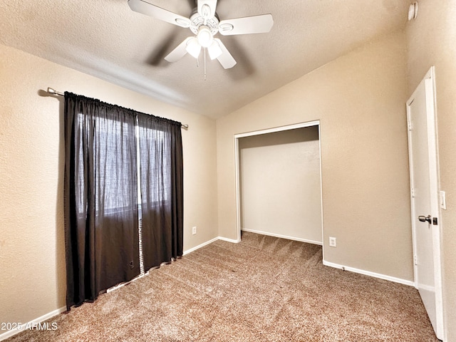 unfurnished bedroom with carpet flooring, lofted ceiling, baseboards, a textured ceiling, and a ceiling fan