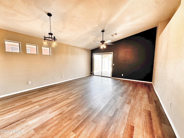 spare room featuring wood finished floors, a ceiling fan, a textured ceiling, baseboards, and lofted ceiling