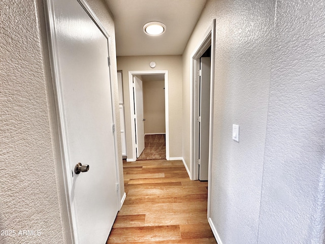 hallway featuring a textured wall and light wood finished floors