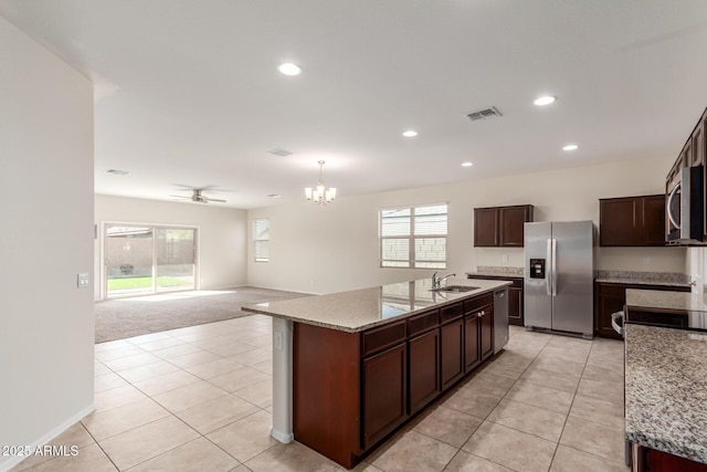 kitchen with ceiling fan with notable chandelier, sink, appliances with stainless steel finishes, and a kitchen island with sink