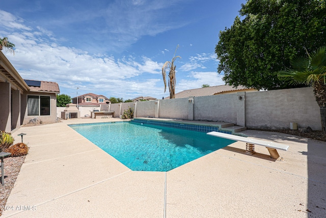 view of swimming pool with a diving board and a patio area