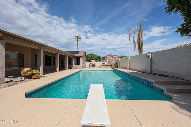 view of swimming pool with a diving board and a patio area