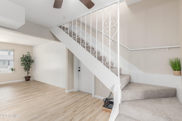 stairs featuring a ceiling fan, baseboards, and wood finished floors