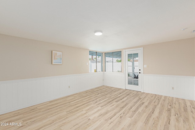 unfurnished room with a wainscoted wall and light wood-type flooring