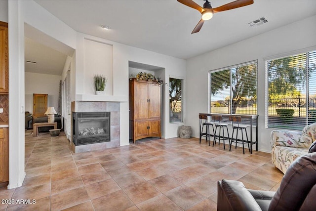 living room with ceiling fan and a tiled fireplace