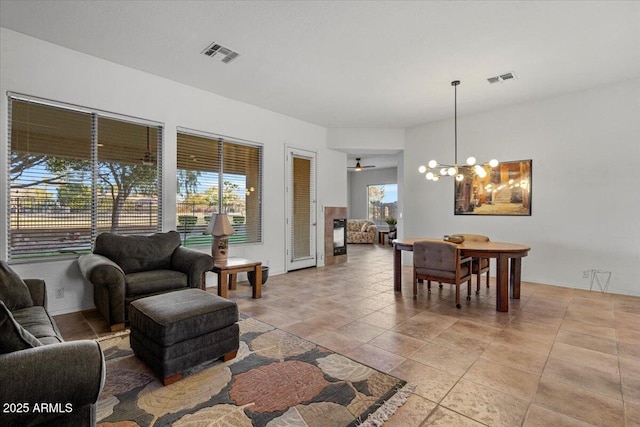 tiled living room featuring ceiling fan with notable chandelier