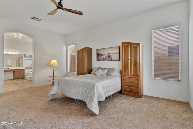 carpeted bedroom with ensuite bathroom and ceiling fan