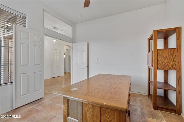 unfurnished office featuring ceiling fan and a towering ceiling