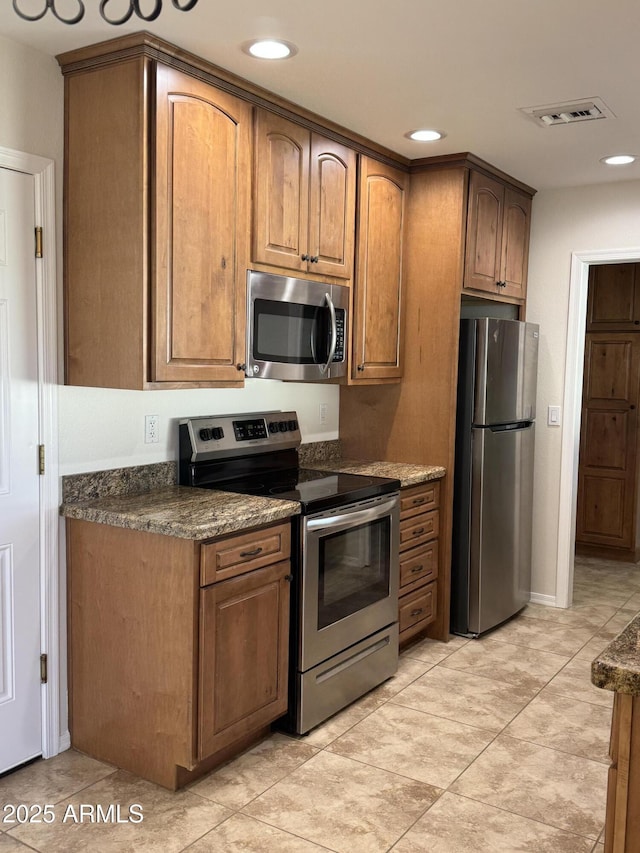 kitchen with appliances with stainless steel finishes and dark stone counters