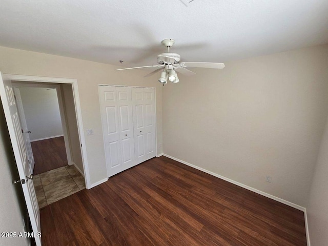 unfurnished bedroom with dark wood-type flooring, ceiling fan, and a closet