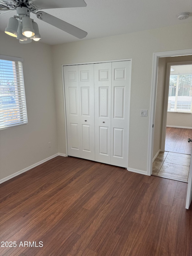 unfurnished bedroom featuring dark hardwood / wood-style flooring, a closet, and ceiling fan