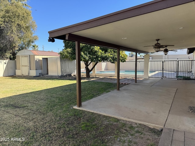 view of yard featuring a fenced in pool, a patio area, ceiling fan, and a storage shed