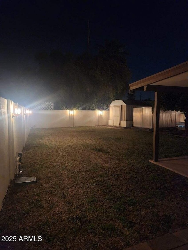 yard at night featuring a storage shed