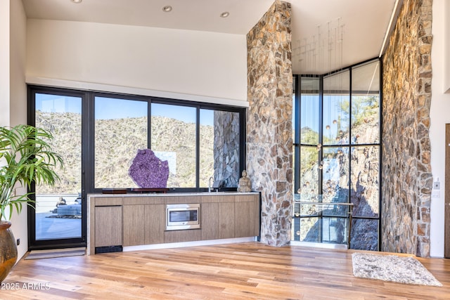 interior space with plenty of natural light, wood finished floors, and a towering ceiling