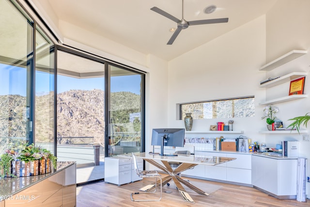 home office with light wood-style floors, ceiling fan, and high vaulted ceiling