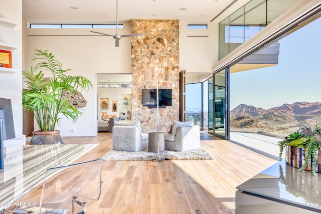 living area with hardwood / wood-style flooring, a high ceiling, and ceiling fan