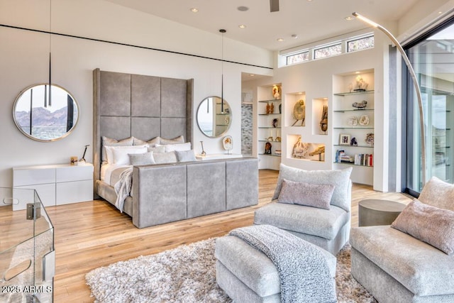 bedroom with recessed lighting, wood finished floors, and a towering ceiling