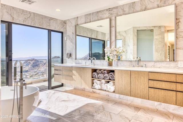 full bathroom with a freestanding tub, visible vents, marble finish floor, a sink, and double vanity