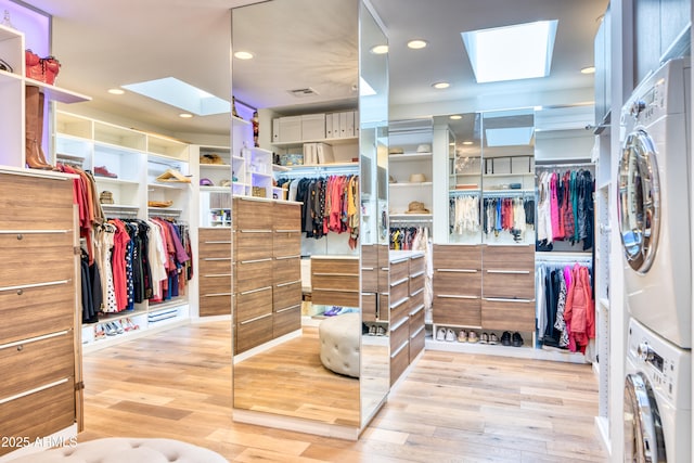 walk in closet featuring stacked washer / dryer, a skylight, and wood finished floors