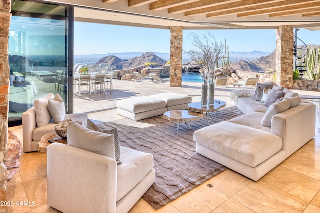 living room with beam ceiling, a healthy amount of sunlight, and a mountain view