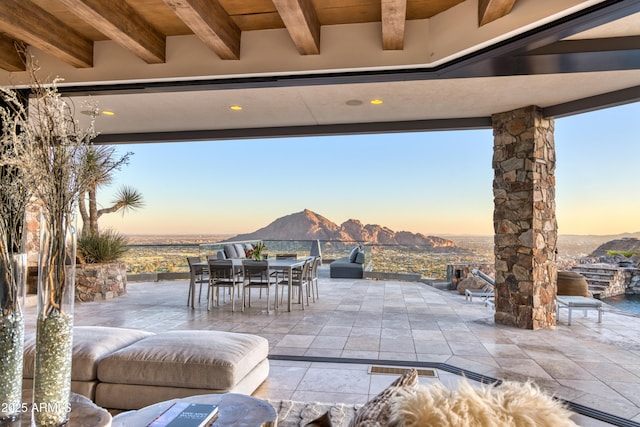 patio terrace at dusk with outdoor dining space and a mountain view