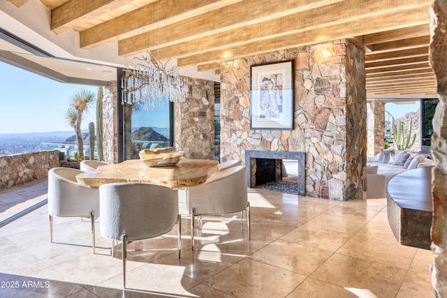 dining room featuring a stone fireplace and beamed ceiling