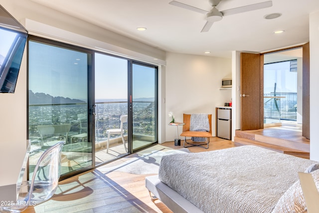 bedroom with recessed lighting, light wood-style floors, freestanding refrigerator, and access to outside