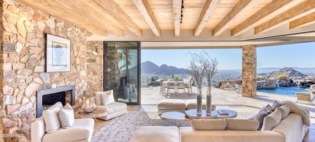 living room with beam ceiling, a mountain view, a fireplace, and wood ceiling