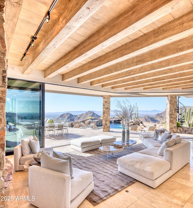 interior space with wooden ceiling, beamed ceiling, rail lighting, and a mountain view