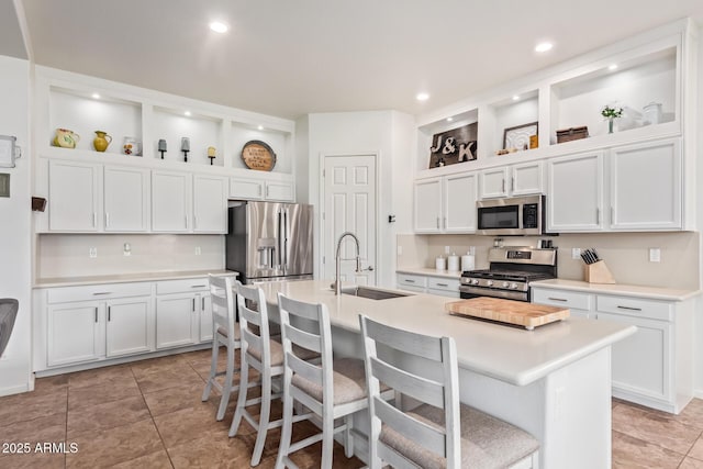 kitchen featuring a kitchen bar, sink, appliances with stainless steel finishes, an island with sink, and white cabinets