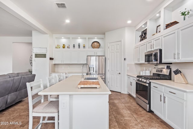 kitchen with stainless steel appliances, a kitchen breakfast bar, an island with sink, and white cabinets