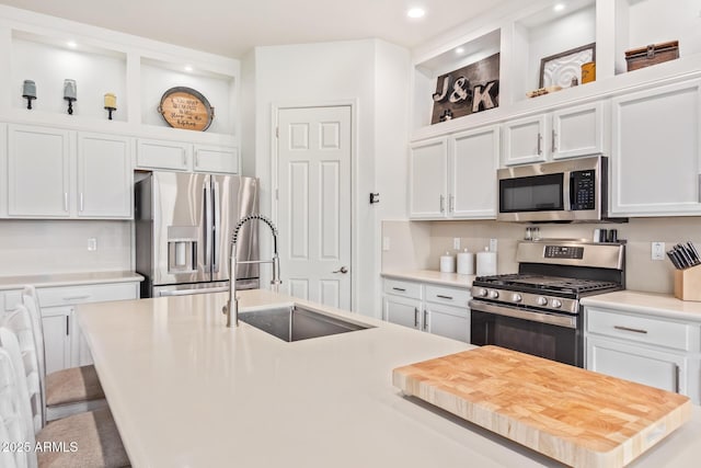 kitchen with a breakfast bar, sink, white cabinetry, stainless steel appliances, and a kitchen island with sink