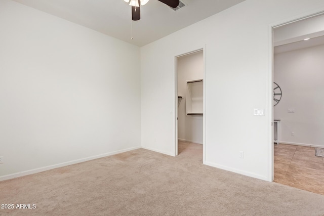 unfurnished bedroom featuring ceiling fan, a spacious closet, a closet, and light carpet