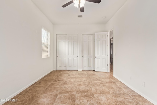 unfurnished bedroom with two closets and ceiling fan