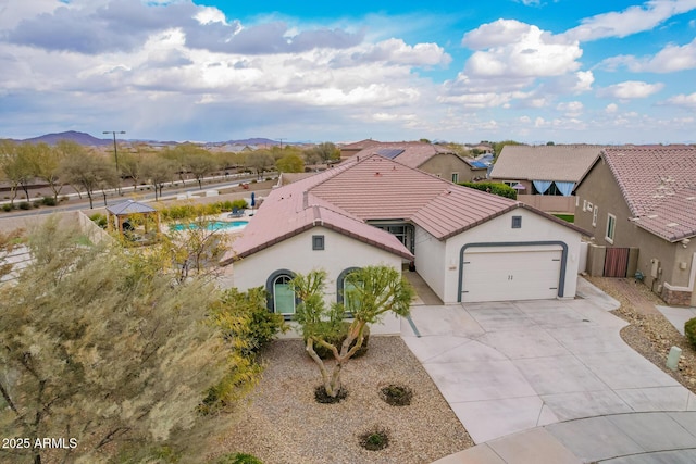 view of front of home with a pool, a garage, and a mountain view