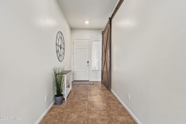 hallway with a barn door and light tile patterned floors