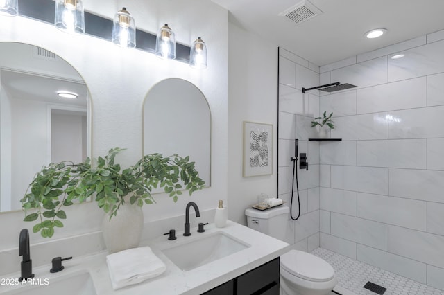 bathroom featuring vanity, toilet, and a tile shower