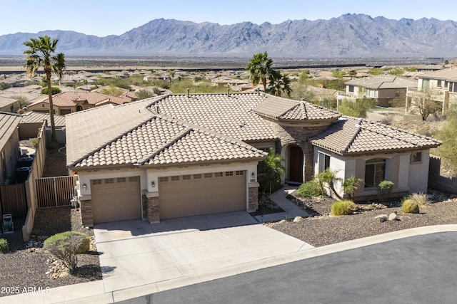 view of front of property featuring fence, driveway, an attached garage, a tile roof, and a mountain view