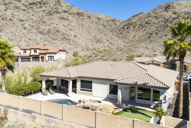 rear view of property featuring stucco siding, a tile roof, a patio, a fenced backyard, and a mountain view