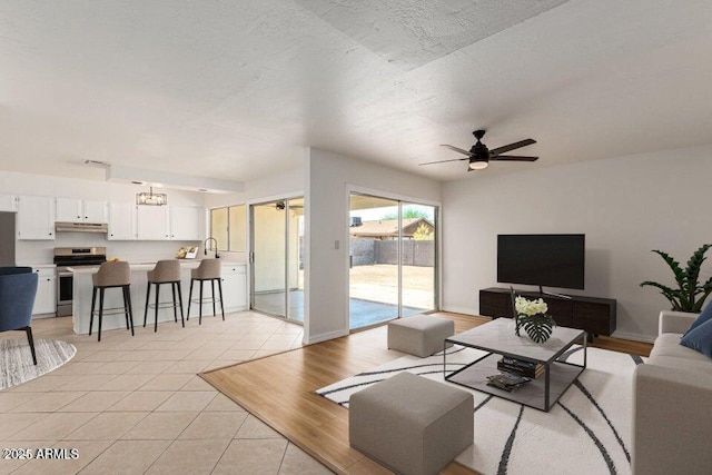 living room with ceiling fan with notable chandelier and light tile patterned floors