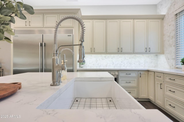 kitchen featuring light stone counters, cream cabinetry, and stainless steel built in fridge