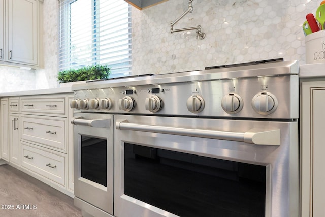 interior details with white cabinetry, stainless steel range, and decorative backsplash