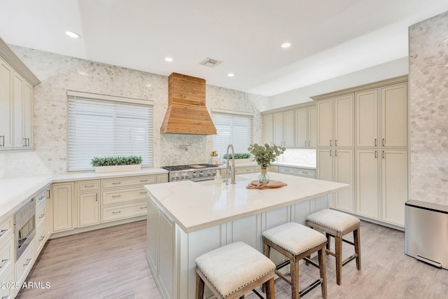 kitchen featuring cream cabinets, custom range hood, and a kitchen breakfast bar