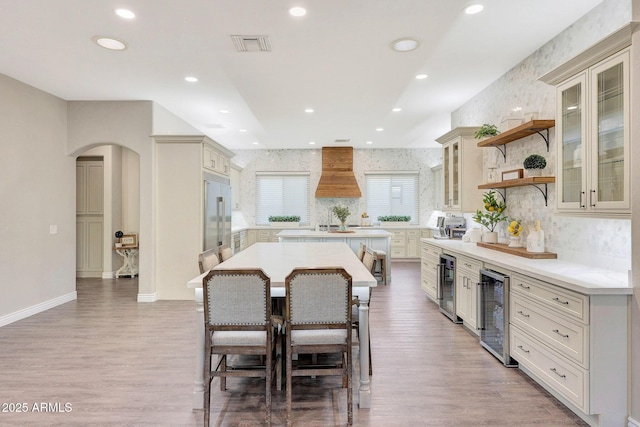 kitchen with a kitchen bar, premium range hood, beverage cooler, and a kitchen island