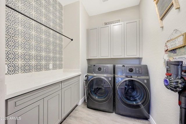 laundry room featuring light hardwood / wood-style flooring, washing machine and dryer, and cabinets