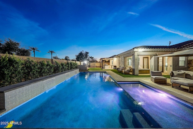 pool at dusk with outdoor lounge area and pool water feature